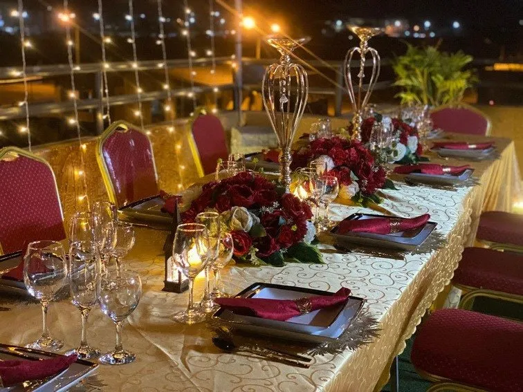 Table de gala dressée en longueur, verrerie et compositions florales basses