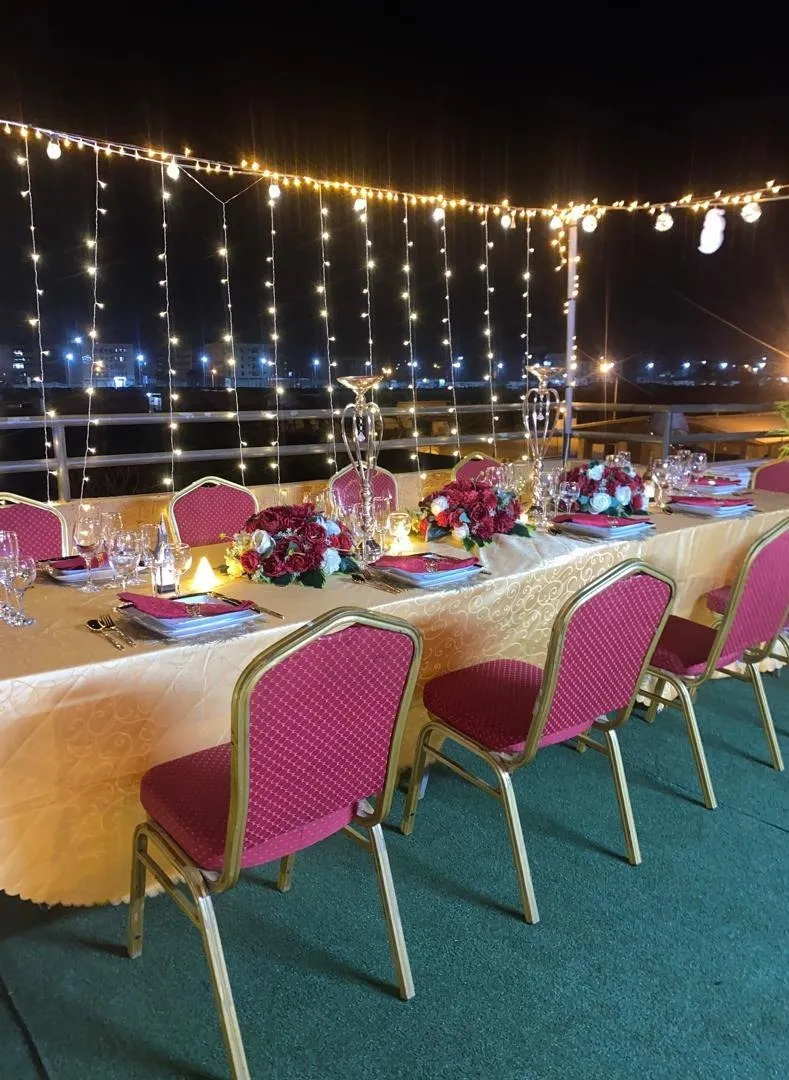 Table de réception dressée en terrasse, de nuit, sous guirlandes