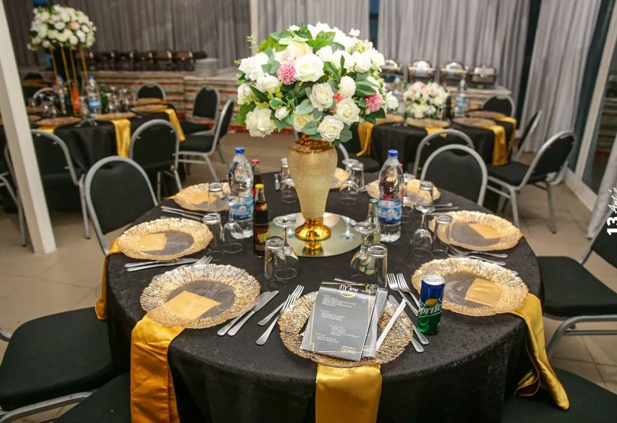 Table ronde dressée, nappage sombre, chemins de table dorés et assiettes de présentation
